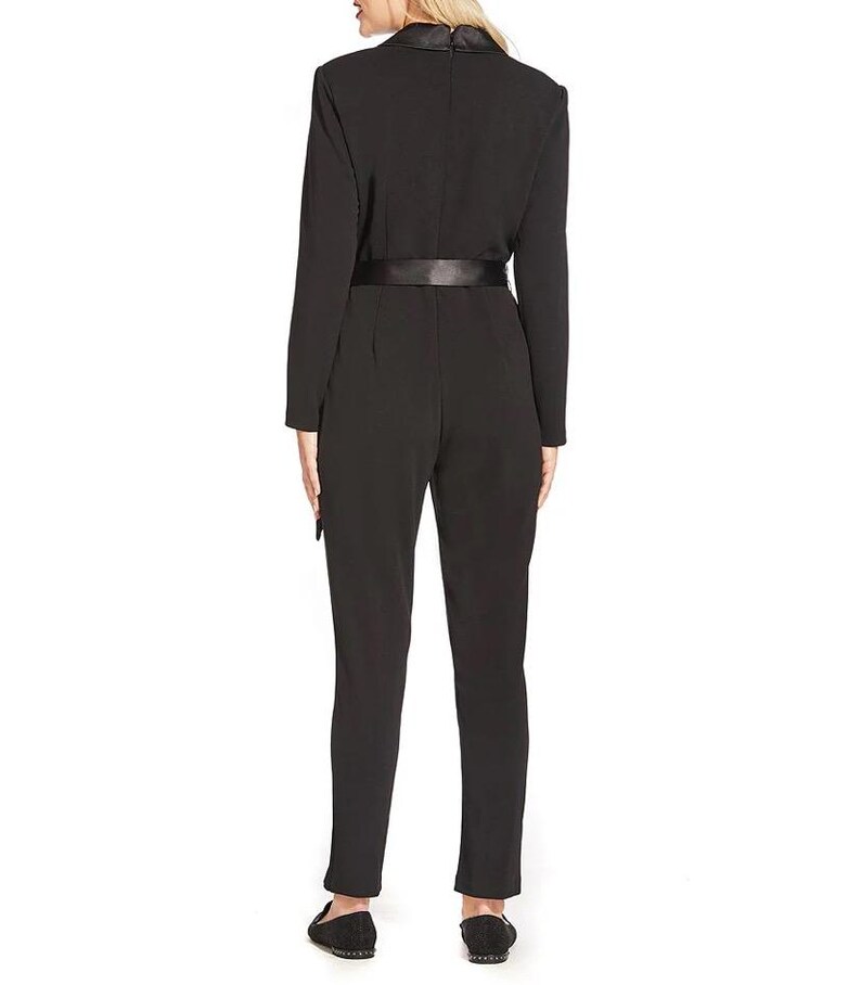 May include: A black jumpsuit with a satin belt and long sleeves. The jumpsuit has a mock neck and a fitted silhouette.