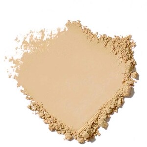 May include: A close-up of a light beige powder product, possibly a cosmetic, against a white background. The powder is finely milled, with a smooth, even surface and a slightly textured edge. The shape is irregular, with a rectangular form.
