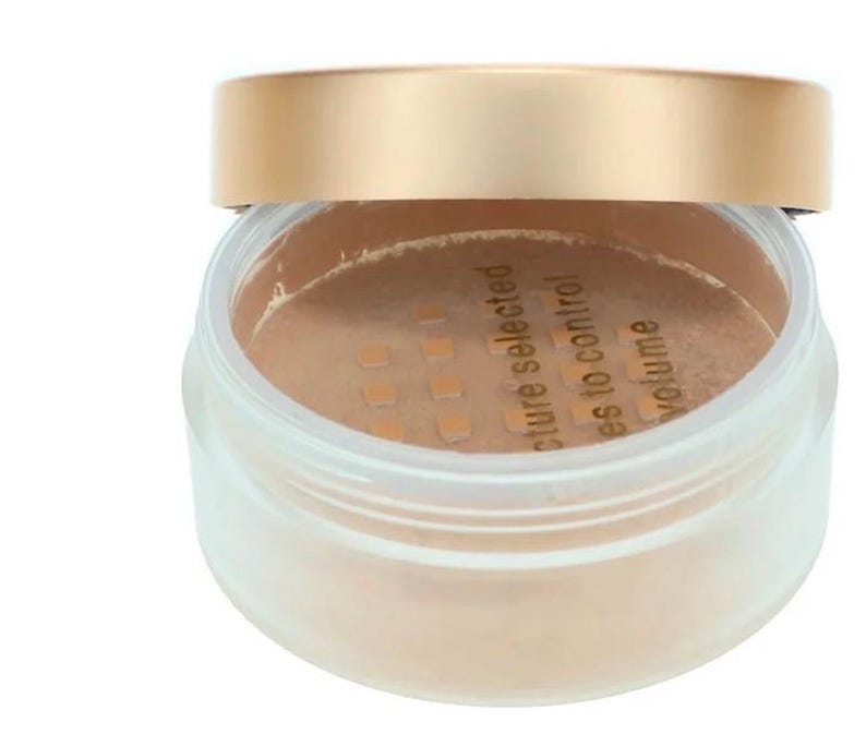 May include: A clear, round cosmetic jar with a gold-colored lid. The jar contains a light beige powder. Text on the powder reads "texture selected, es to control, volume".