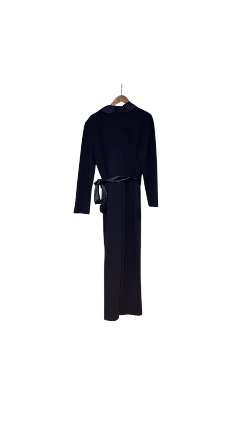 May include: A black long-sleeved jumpsuit with a satin sash tie at the waist.