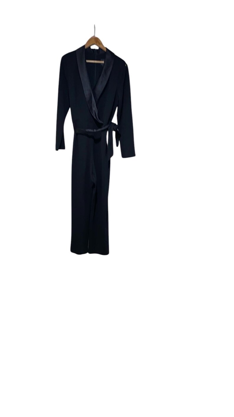 May include: A black jumpsuit with a satin lapel and a tie belt.