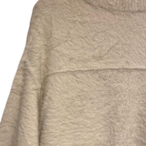 May include: A white fuzzy sweater with a crew neck and long sleeves.
