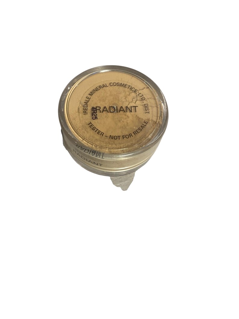 May include: A small, round container of Iredale Mineral Cosmetics Radiant powder. The lid is tan with the word "RADIANT" in the center. The text "TESTER - NOT FOR RESALE" is printed on the lid. The container is filled with a light beige powder.
