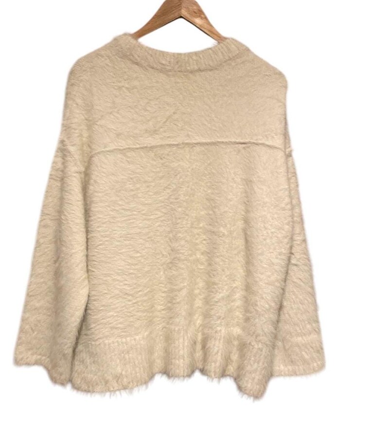 May include: A fluffy white sweater with a crew neck and long sleeves. The sweater has a slightly oversized fit and a relaxed silhouette.
