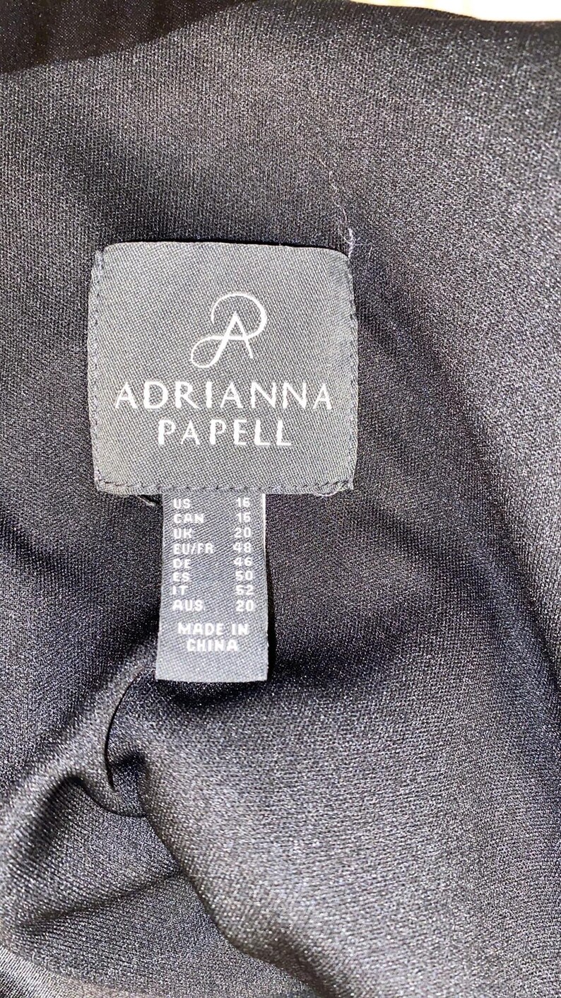 May include: A black tag with white text that reads "R ADRIANNA PAPELL" and size information for US, CAN, UK, EU/FR, DE, ES, IT, and AUS. The tag also says "MADE IN CHINA".