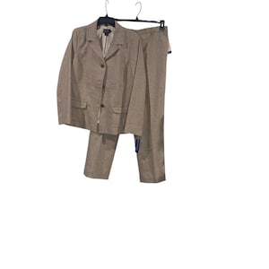 May include: A two-piece tan suit set, including a blazer and matching trousers, hanging on a black hanger. The blazer has two front pockets and button closures. The trousers are straight-legged. A tag is attached to the trousers.