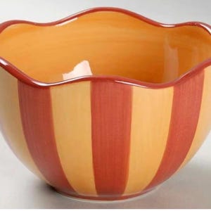 May include: A ceramic bowl with a wavy rim, featuring alternating vertical stripes of orange and red. The interior of the bowl is a solid orange color, creating a vibrant and decorative piece.