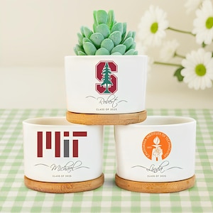 May include: Three white ceramic planters with bamboo saucers, each featuring a different university logo and a name. One planter has a Stanford logo, one has an MIT logo, and the last has a Caltech logo. Each planter has a succulent.