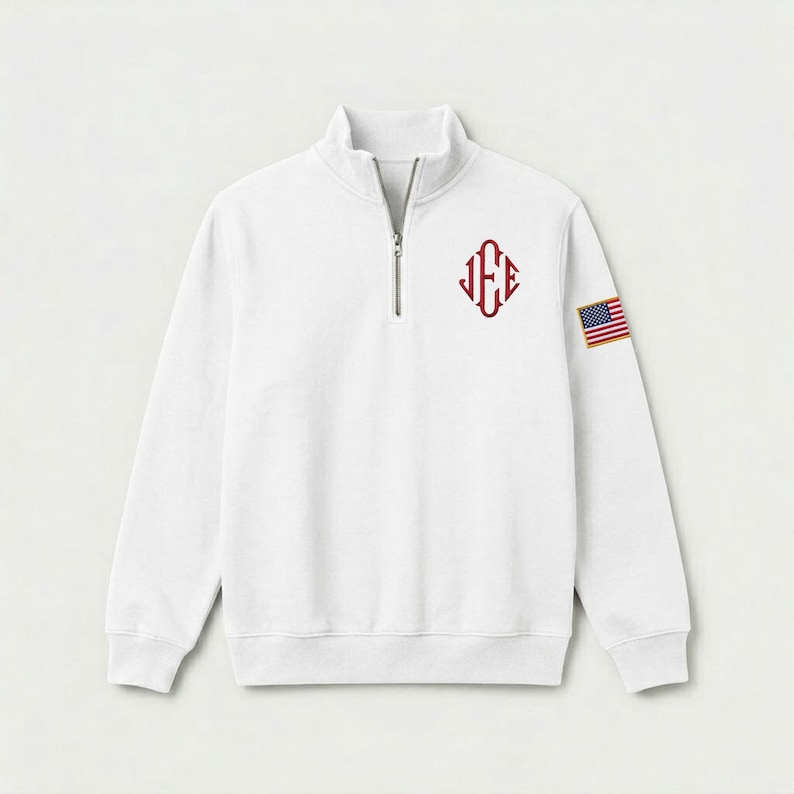 May include: A white long-sleeve quarter-zip pullover sweatshirt featuring a maroon monogram with the letters J, E, and E arranged in a diamond shape on the left chest and a small rectangular American flag patch on the upper left sleeve.