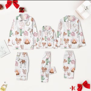 Puede incluir: Conjuntos de pijama blancos con estampado de tem&aacute;tica occidental. Los conjuntos incluyen camisas con botones y pantalones, con cactus, caballos, sillas de montar y atrapasue&ntilde;os en estilo acuarela. Los pijamas tienen ribetes blancos.