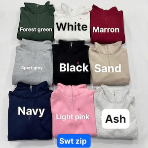 May include: A collection of nine quarter-zip sweatshirts in various colors including forest green, white, maroon, sport grey, black, sand, navy, light pink, and ash. Each sweatshirt features a high collar with a central zipper closure.