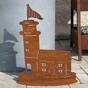 Könnte beinhalten: Eine rostige Metallsilhouette eines Leuchtturms mit einer Flagge oben. Die Silhouette steht auf einem braunen Sockel. Der Leuchtturm hat ein kleines Haus daran.