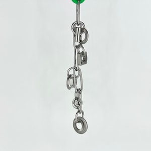 May include: A silver chain with multiple metal rings and a small padlock attached. The chain is hanging from a green object.