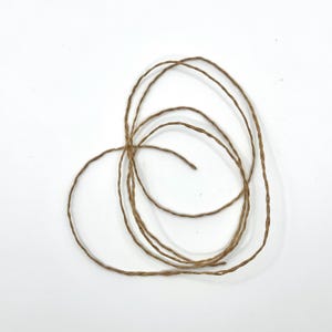 Könnte beinhalten: Eine weiße Keramik-Tasse mit schwarzem Henkel und dem Text "But First, Coffee" in schwarzer, handschriftlicher Schrift. Die Tasse steht auf einer weißen Oberfläche.