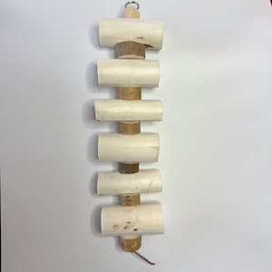May include: A wooden pet toy with a series of light-coloured cylindrical blocks and small, round wood pieces. A small metal ring is at the top for hanging. The toy is designed for small animals.