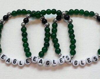 May include: Three green beaded bracelets with silver and black beads. Each bracelet has the word "EAGLES" spelled out in white letters.