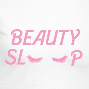 Puede incluir: Camiseta blanca con texto rosa que dice "BEAUTY SLEEP" con pestañas rosas a cada lado de la palabra "SLEEP".