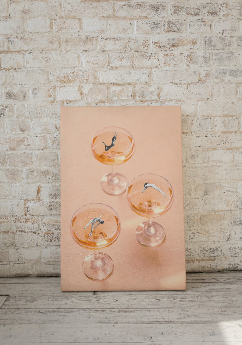 May include: Three champagne flutes filled with a pale orange liquid. Each flute contains a small figure of a person diving into the liquid.