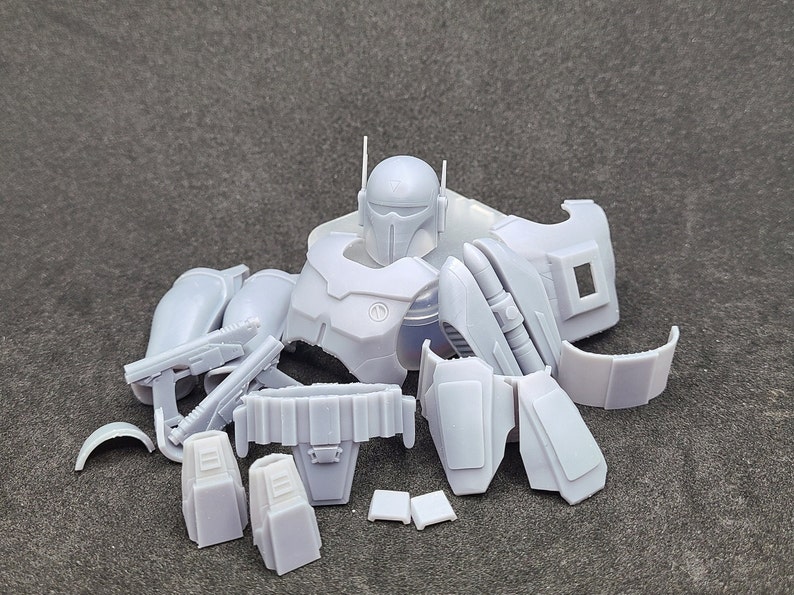 May include: A set of unassembled white plastic parts for a Mandalorian action figure. The parts include the head, torso, arms, legs, and weapons.