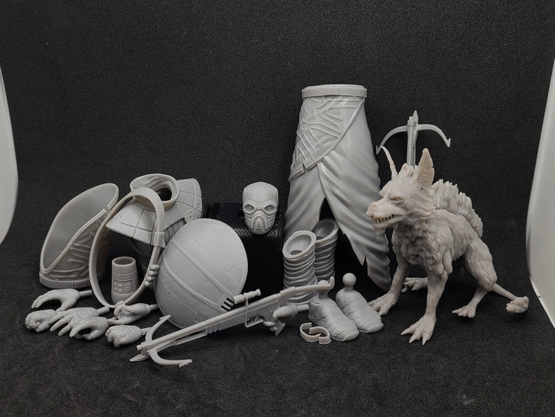 Pu&ograve; includere: Un set di miniature stampate in 3D di colore grigio, tra cui una creatura simile a un lupo, un elmo, una balestra e vari pezzi di armatura.