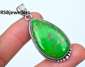 May include: A silver pendant with a green and gold turquoise stone. The stone is set in a silver bezel and has a teardrop shape. The pendant is on a silver chain.