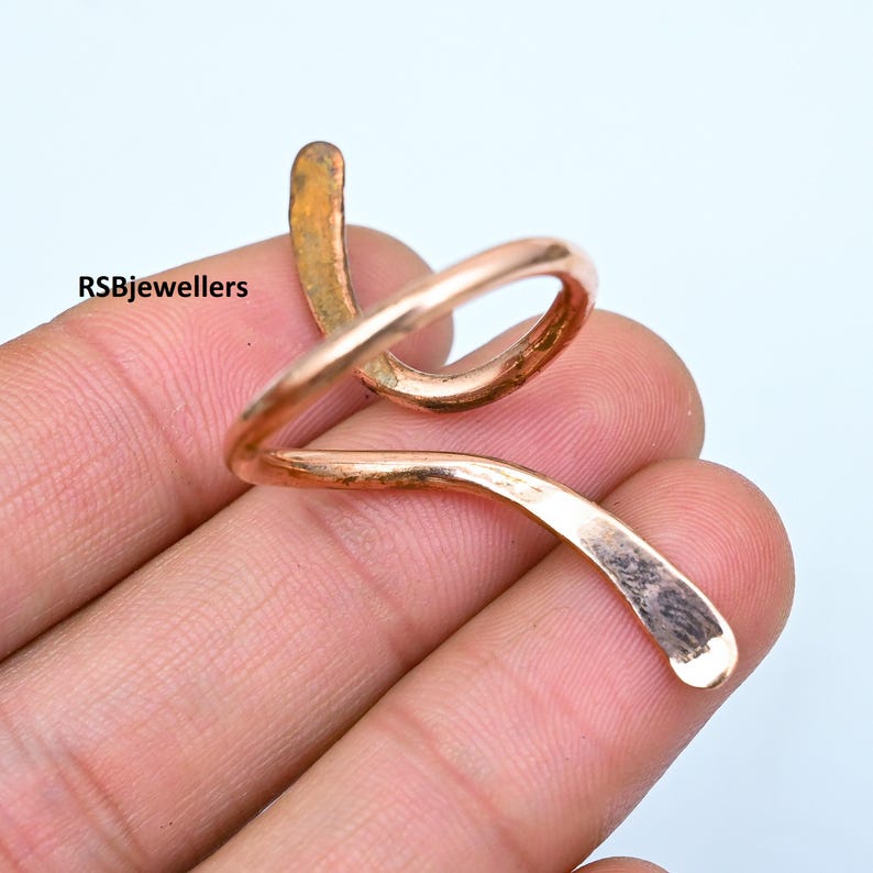 May include: A copper wire ring with a spiral design. The ring is open and can be adjusted to fit different finger sizes.