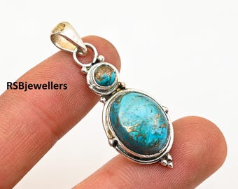 May include: A silver pendant with a large oval turquoise stone and a smaller round turquoise stone. The stones have a blue and green color with gold flecks.