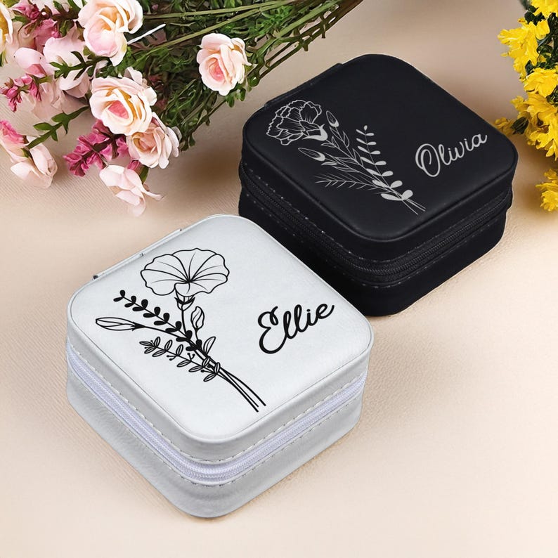 Puede incluir: Dos peque&ntilde;as cajas cuadradas de joyer&iacute;a con dise&ntilde;os florales y nombres personalizados. La caja de la izquierda es blanca con un dise&ntilde;o floral negro y el nombre "Ellie". La caja de la derecha es negra con un dise&ntilde;o floral blanco y el nombre "Olivia".