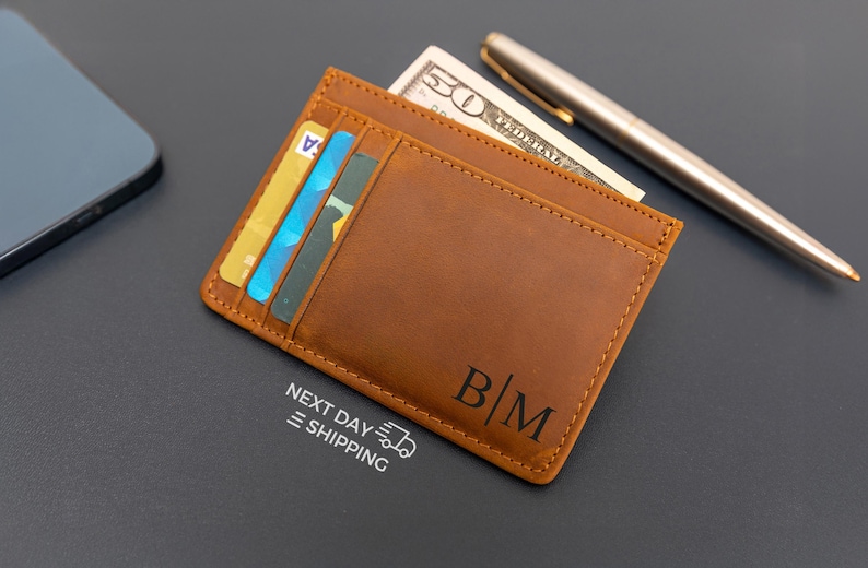 May include: A brown leather wallet with a card slot and a monogrammed "B/M" on the front.