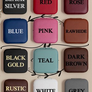 Puede incluir: Doce cajas cuadradas para anillos en varios colores, incluyendo negro, rojo, rosa, azul, rosa, cuero crudo, oro negro, turquesa, marr&oacute;n oscuro, oro r&uacute;stico, blanco y gris. Cada caja tiene un color diferente y una etiqueta de texto que indica el color.