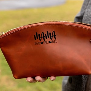 May include: A brown leather zippered pouch with the text "MAMA" and the names "David, Emily, Alex" with hearts between each name.