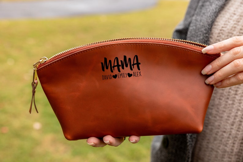 May include: A brown leather zippered pouch with the text "MAMA" and the names "David, Emily, Alex" with hearts between each name.
