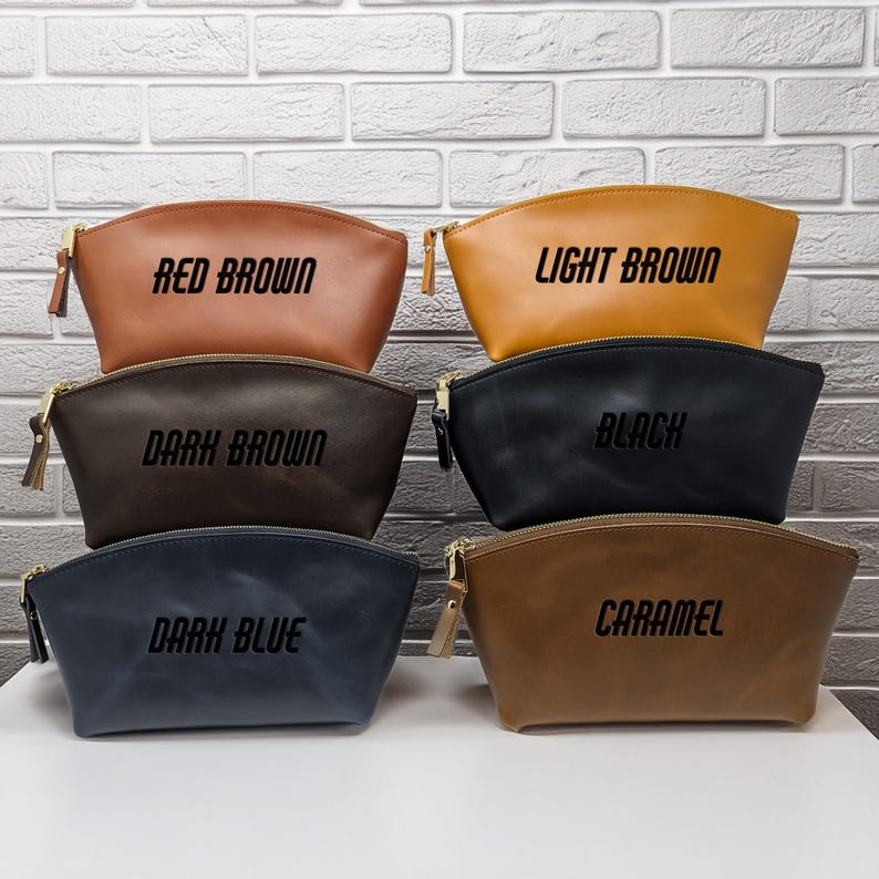 May include: Five different colored leather cosmetic bags with zipper closures. The bags are labeled "Red Brown", "Light Brown", "Black", "Dark Blue", and "Caramel".