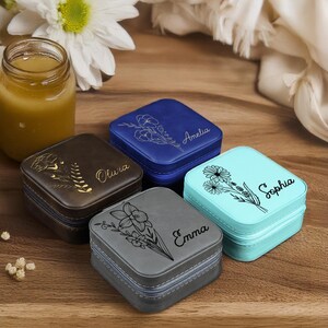 Puede incluir: Cuatro peque&ntilde;as cajas cuadradas de joyer&iacute;a con dise&ntilde;os florales y nombres personalizados: Olivia, Amelia, Sophia y Emma. Las cajas son de color marr&oacute;n, azul, turquesa y gris.