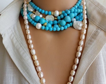 May include: A layered necklace featuring turquoise beads, white pearls, and gold accents. A long strand of off-white pearls drapes down. The necklace is displayed on a mannequin, against a neutral-colored shirt.