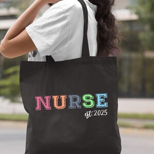 May include: Black tote bag with the word "NURSE" in rainbow colours and the text "est. 2025" underneath.