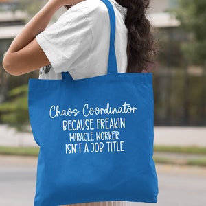 Puede incluir: Una bolsa de tela azul real con texto blanco que dice "Chaos Coordinator Because Freakin Miracle Worker Isn't A Job Title".