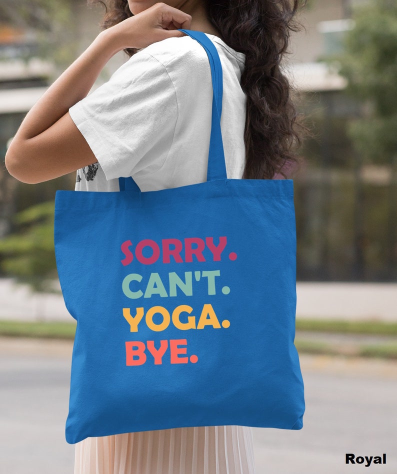 Puede incluir: Una bolsa de tela azul real con el texto "SORRY. CAN'T. YOGA. BYE." en letras de colores.