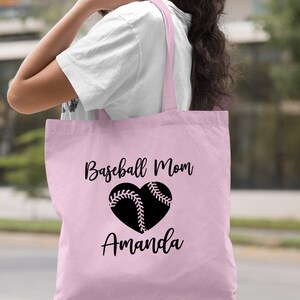May include: A light pink tote bag with black text that reads "Baseball Mom" and a black heart with a baseball inside. The name "Amanda" is written below the heart.