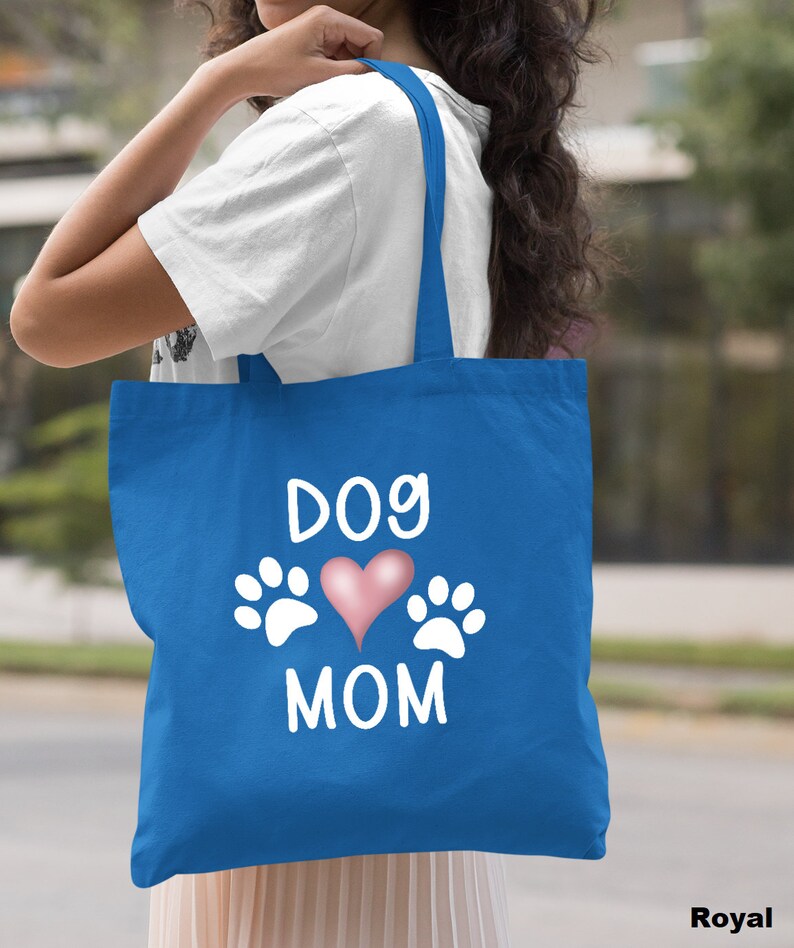 May include: A royal blue tote bag with white text that says "Dog Mom" and a pink heart with white paw prints on either side of the heart.