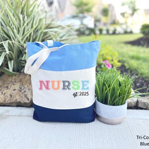 May include: A blue, white and navy blue tote bag with the word "NURSE" in rainbow colours and the text "est. 2025".