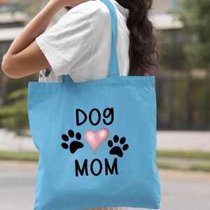 May include: Light blue tote bag with the text "Dog Mom" and a pink heart with paw prints on either side.