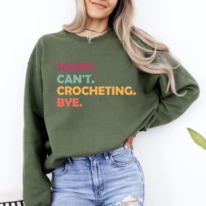May include: A green sweatshirt with the text "Sorry. Can't. Crocheting. Bye." in colorful letters.