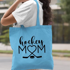May include: Light blue tote bag with black text that reads "hockey MOM" with a heart in place of the "O".  Two hockey sticks are crossed below the text with a puck in the center.