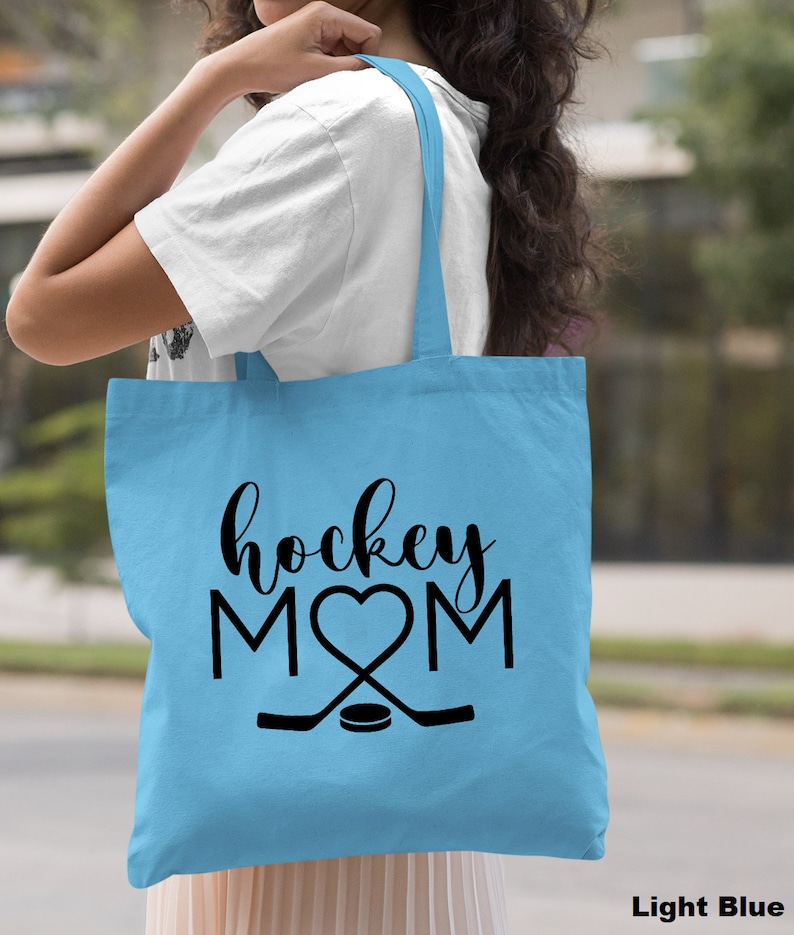 May include: Light blue tote bag with black text that reads "hockey MOM" with a heart in place of the "O".  Two hockey sticks are crossed below the text with a puck in the center.