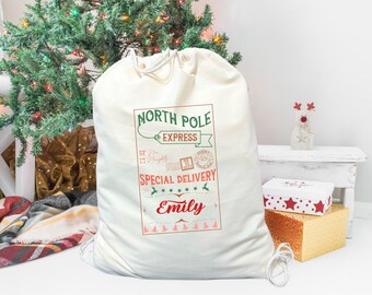 May include: A white canvas Santa sack with a red and green North Pole Express design. The sack has a drawstring closure and the text "Special Delivery for Emily" is printed on the front.