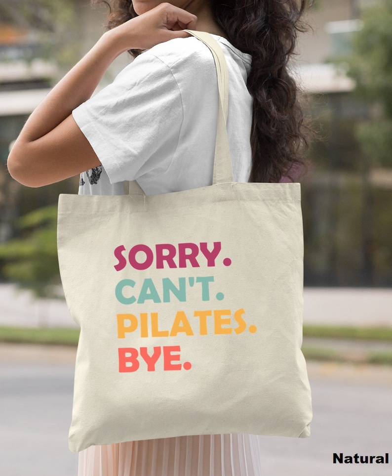 May include: A natural canvas tote bag with the text "SORRY. CAN'T. PILATES. BYE." in colorful letters.