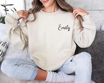 Puede incluir: Una sudadera de color crema con el nombre "Emily" bordado en la parte delantera.