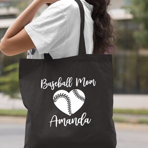 May include: Black canvas tote bag with white text that reads "Baseball Mom Amanda" and a white baseball in a heart shape.