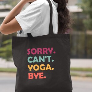Puede incluir: Bolsa de lona negra con el texto "SORRY. CAN'T. YOGA. BYE." en letras de colores.